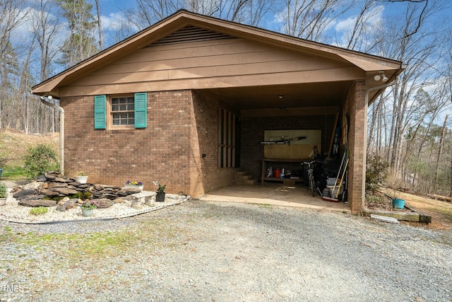 view of side of home with gravel driveway and brick siding