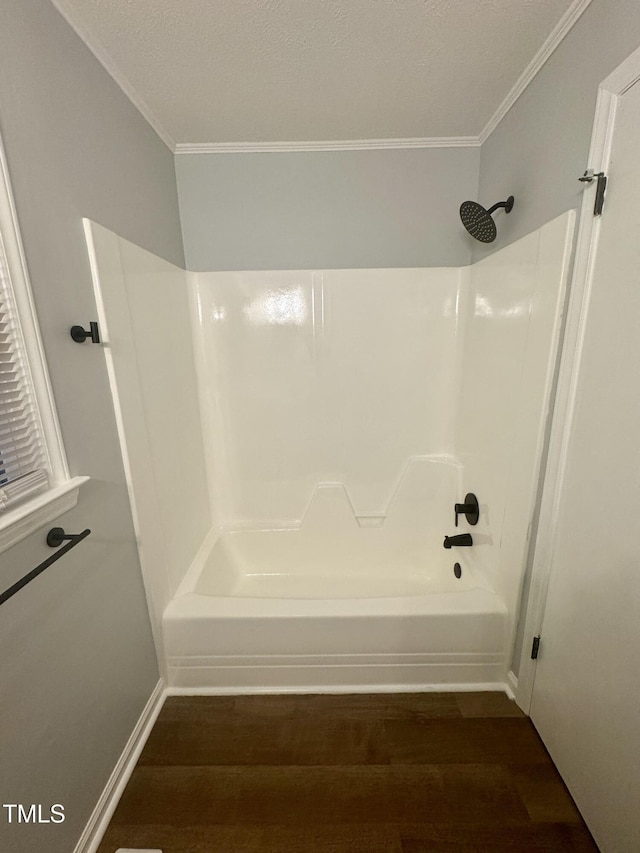 bathroom featuring shower / bathtub combination, ornamental molding, wood finished floors, and baseboards