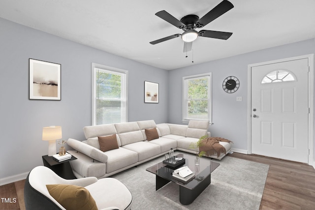 living area featuring wood finished floors, baseboards, and a ceiling fan