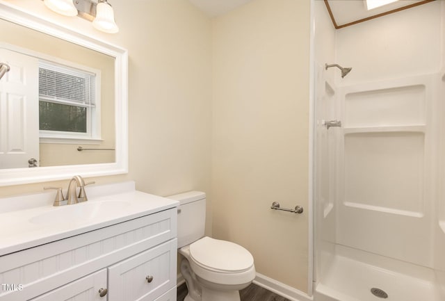 bathroom featuring toilet, wood finished floors, vanity, baseboards, and a stall shower