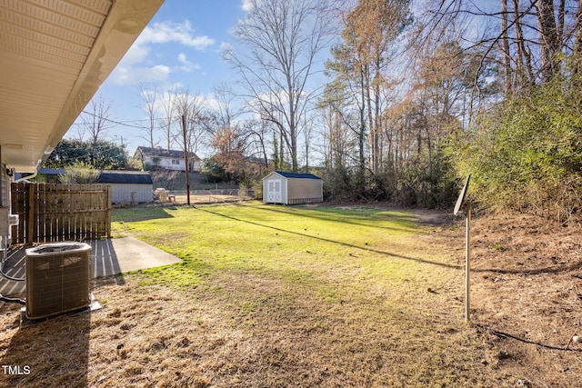 view of yard with a storage shed, fence, central AC, and an outdoor structure