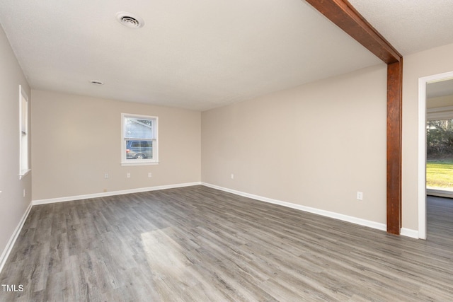 unfurnished room with wood finished floors, visible vents, and baseboards