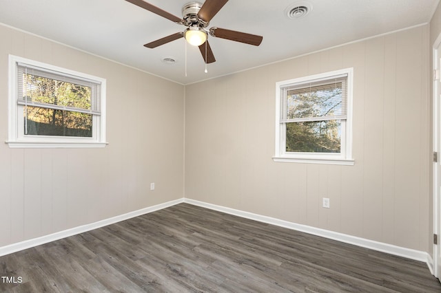 unfurnished room with a healthy amount of sunlight, visible vents, dark wood finished floors, and baseboards