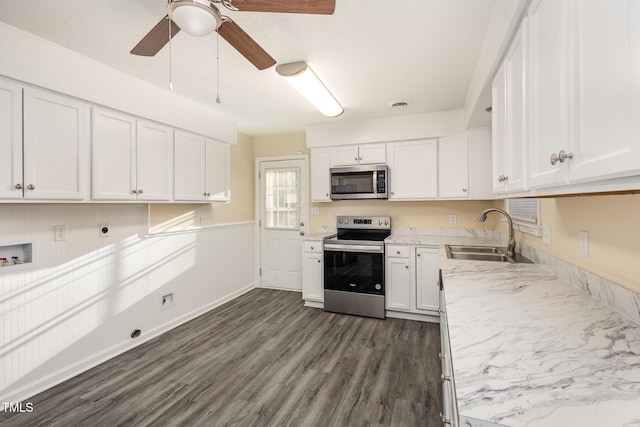 kitchen featuring stainless steel appliances, a sink, a ceiling fan, white cabinets, and dark wood-style floors