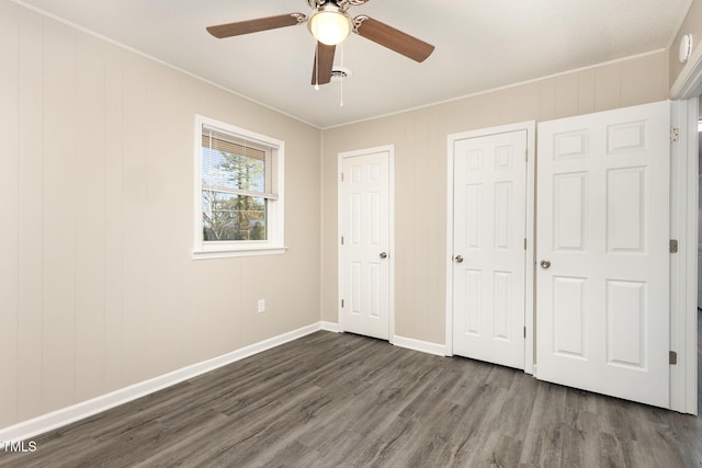 unfurnished bedroom featuring ceiling fan, baseboards, dark wood finished floors, and crown molding