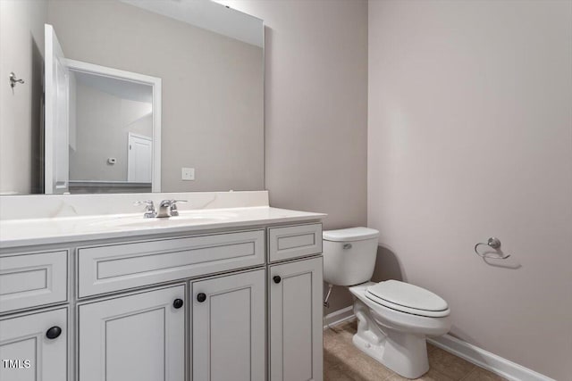 half bathroom featuring tile patterned floors, baseboards, toilet, and vanity