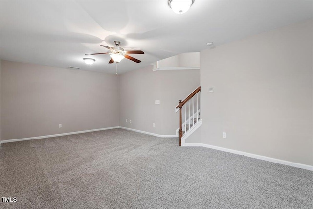 carpeted empty room with stairway, a ceiling fan, and baseboards