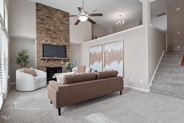 living area featuring visible vents, stairway, carpet flooring, a stone fireplace, and a high ceiling