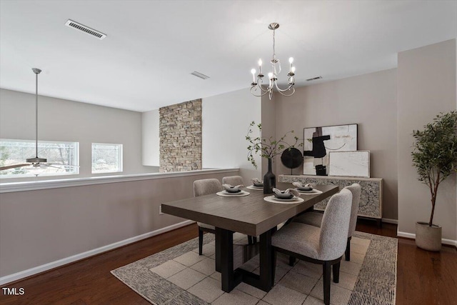 dining area with ceiling fan with notable chandelier, wood finished floors, visible vents, and baseboards