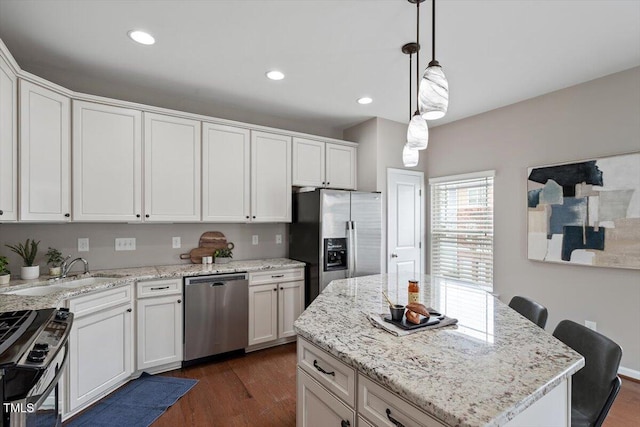 kitchen featuring dark wood finished floors, recessed lighting, stainless steel appliances, hanging light fixtures, and white cabinetry