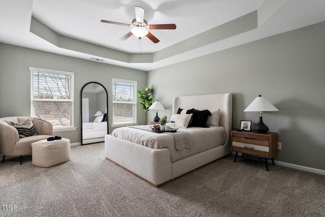 bedroom featuring a tray ceiling, carpet floors, baseboards, and ceiling fan