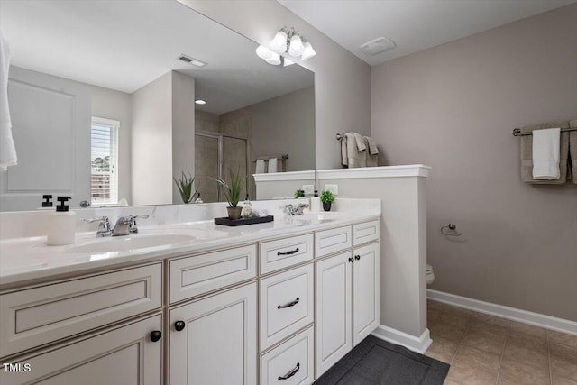 full bathroom featuring double vanity, a stall shower, a sink, tile patterned floors, and toilet