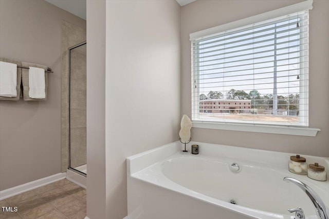 bathroom featuring baseboards, a bath, a shower stall, and tile patterned flooring