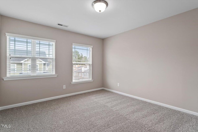 spare room featuring visible vents, baseboards, and carpet