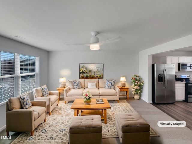 living area featuring ceiling fan, visible vents, and baseboards