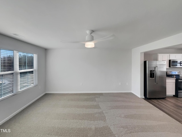 interior space featuring baseboards, stainless steel appliances, ceiling fan, and white cabinets