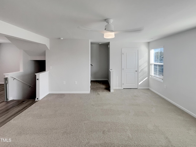 carpeted spare room featuring ceiling fan and baseboards