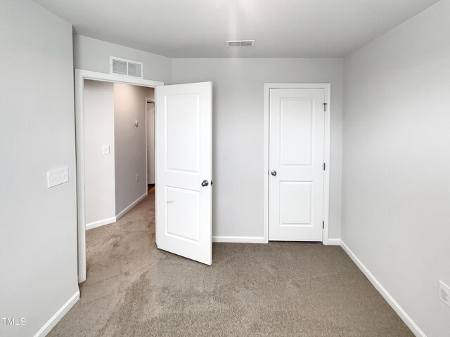 unfurnished bedroom with carpet floors, visible vents, and baseboards