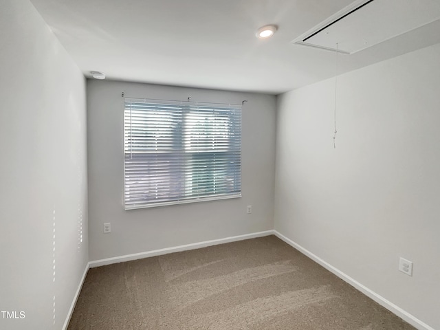 unfurnished room featuring attic access, carpet floors, and baseboards