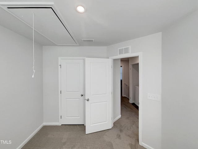 unfurnished bedroom featuring attic access, light colored carpet, visible vents, and baseboards