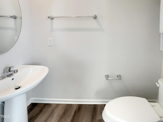 bathroom with toilet, baseboards, and wood finished floors