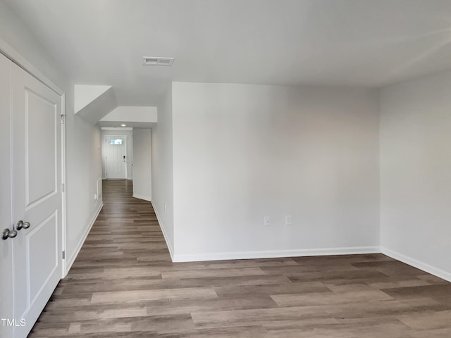 hall featuring wood finished floors, visible vents, and baseboards