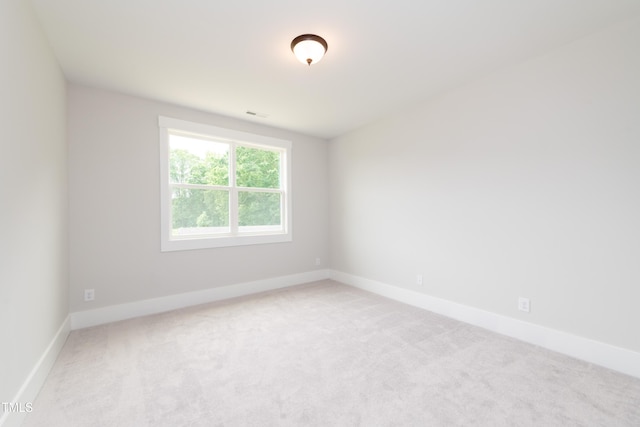 spare room with carpet flooring, visible vents, and baseboards