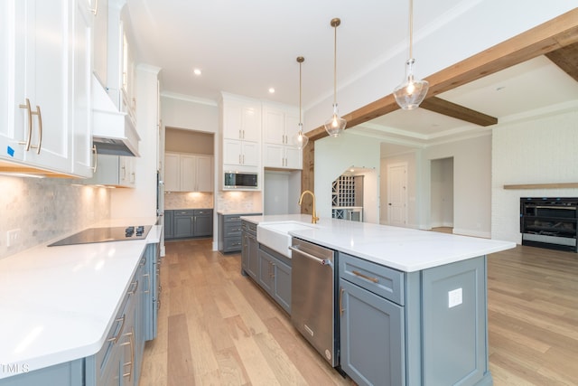 kitchen featuring light wood finished floors, appliances with stainless steel finishes, a sink, and white cabinets