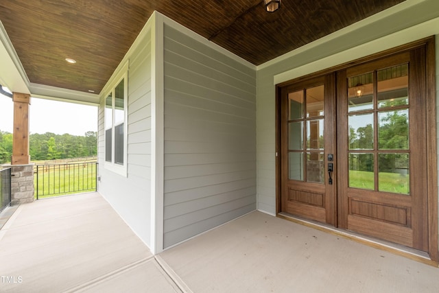 view of exterior entry featuring french doors and a porch