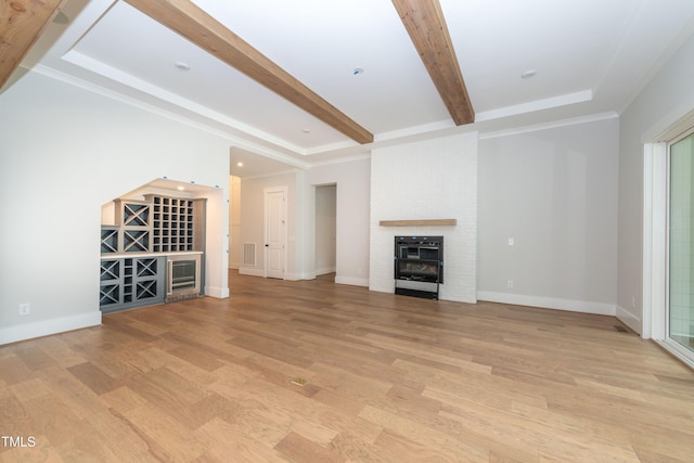 unfurnished living room with a brick fireplace, beam ceiling, light wood-style flooring, and baseboards