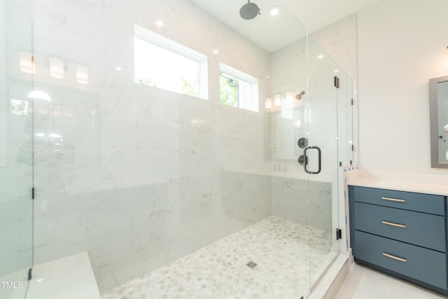 bathroom with tile patterned flooring, a marble finish shower, and vanity