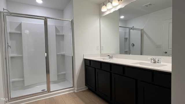 bathroom featuring a stall shower, visible vents, a sink, and wood finished floors