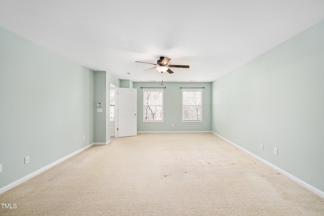 spare room featuring light carpet, ceiling fan, and baseboards