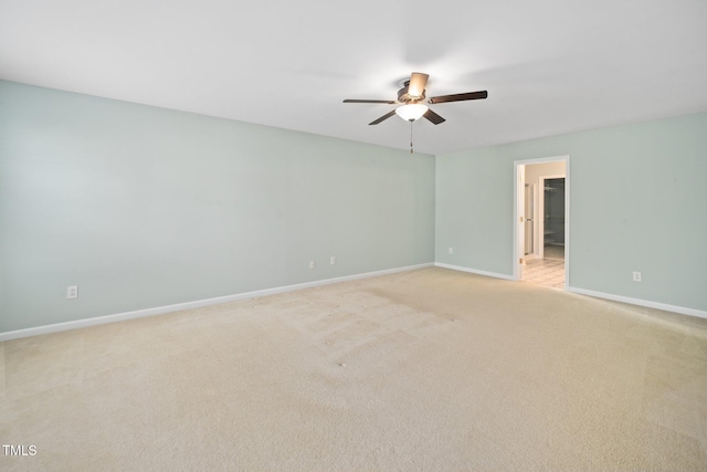 spare room with ceiling fan, light colored carpet, and baseboards