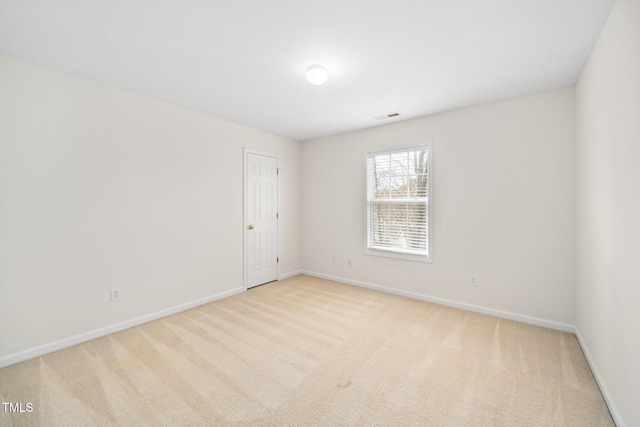 empty room with carpet, visible vents, and baseboards