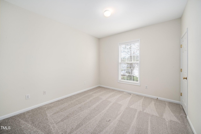 spare room with light colored carpet, visible vents, and baseboards