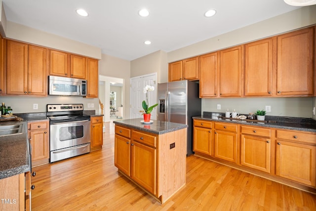 kitchen with stainless steel appliances, a center island, light wood-style floors, and recessed lighting