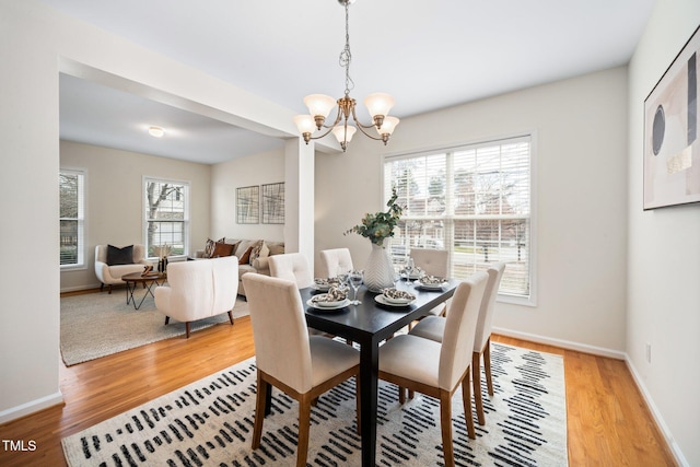 dining area with light wood-style floors, baseboards, and a notable chandelier