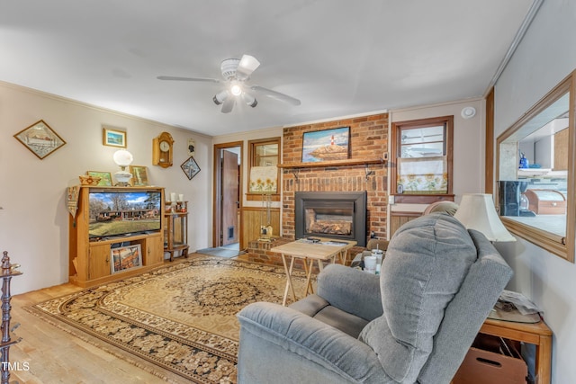 living room with ornamental molding, a fireplace, ceiling fan, and wood finished floors