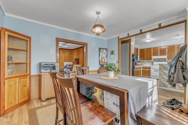 dining space with ornamental molding and light wood-style flooring