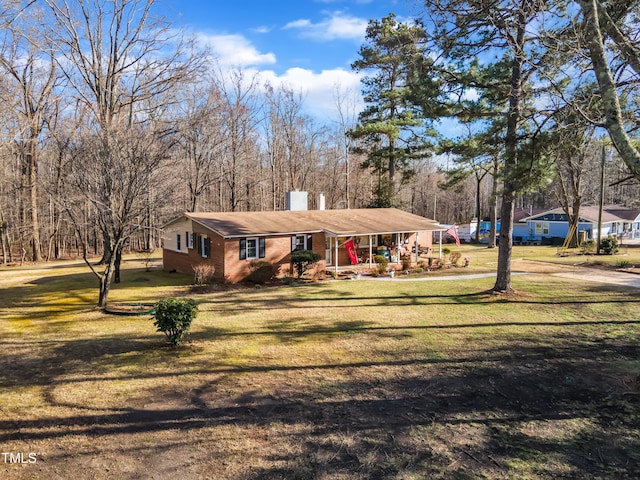 view of front of property featuring a chimney, a front lawn, and brick siding