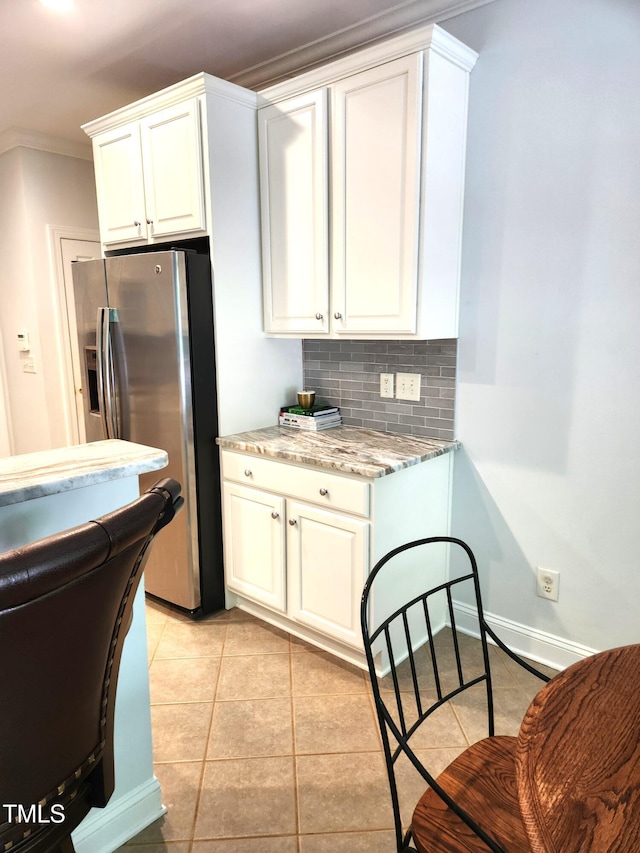 155 Georgetown Woods Dr, Youngsville, NC 27596 - kitchen featuring light stone countertops, decorative backsplash, stainless steel fridge, light tile patterned flooring, and crown molding