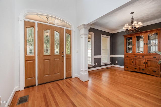 155 Georgetown Woods Dr, Youngsville, NC 27596 - foyer entrance with a chandelier, light wood-style flooring, ornate columns, and crown molding