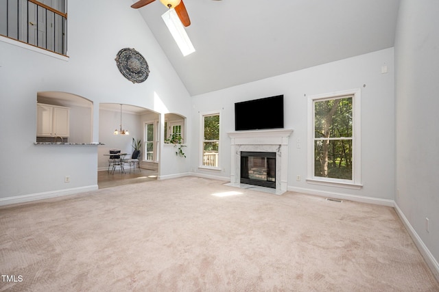 155 Georgetown Woods Dr, Youngsville, NC 27596 - unfurnished living room featuring high vaulted ceiling, light carpet, arched walkways, a fireplace, and a chandelier