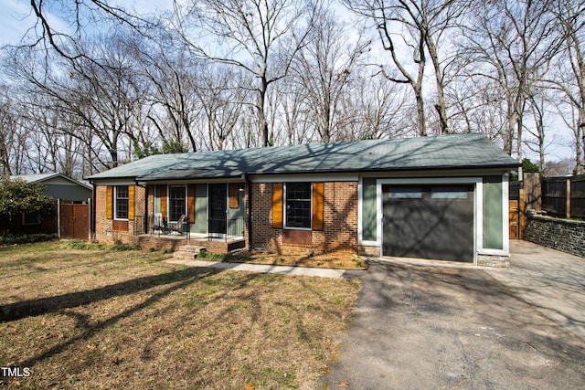 view of front of house with aphalt driveway, an attached garage, fence, a front lawn, and brick siding