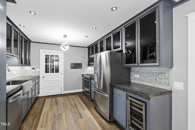 kitchen with dark wood-style floors, stainless steel appliances, glass insert cabinets, a sink, and beverage cooler