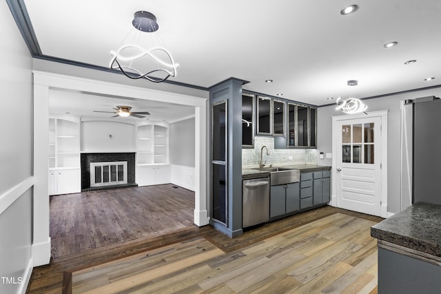 kitchen with crown molding, dark countertops, a sink, and dishwasher