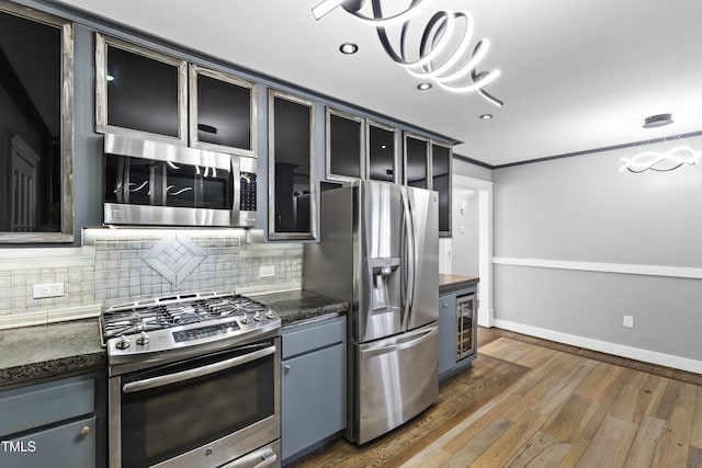 kitchen featuring dark countertops, dark wood-type flooring, stainless steel appliances, and backsplash