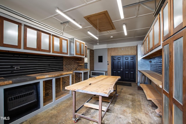 kitchen featuring glass insert cabinets, unfinished concrete flooring, and heating unit