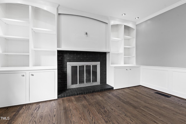 unfurnished living room featuring dark wood-style floors, a brick fireplace, wainscoting, and built in features